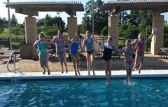 Kids jumping in thye outdoor pool holding hands